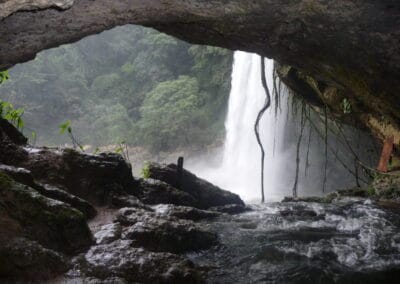 The exit of an imposing, extensive cave system behind a waterfall.